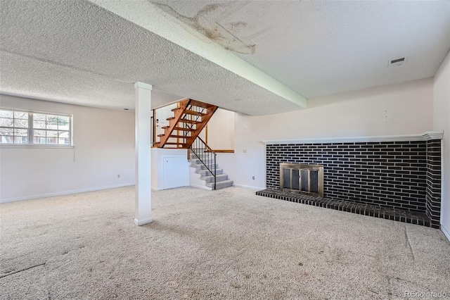 unfurnished living room with carpet floors, a glass covered fireplace, stairs, baseboards, and visible vents