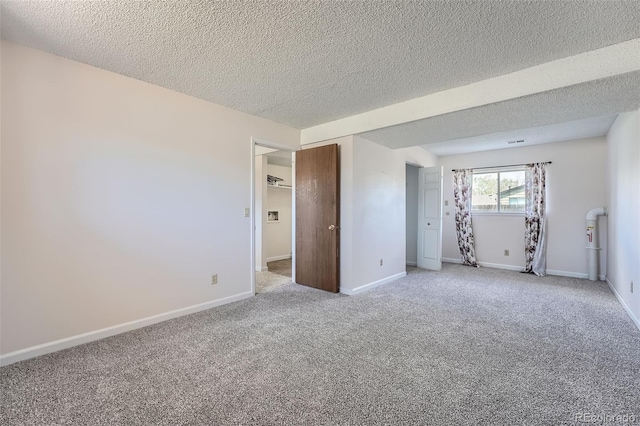 unfurnished room with baseboards, a textured ceiling, and light carpet