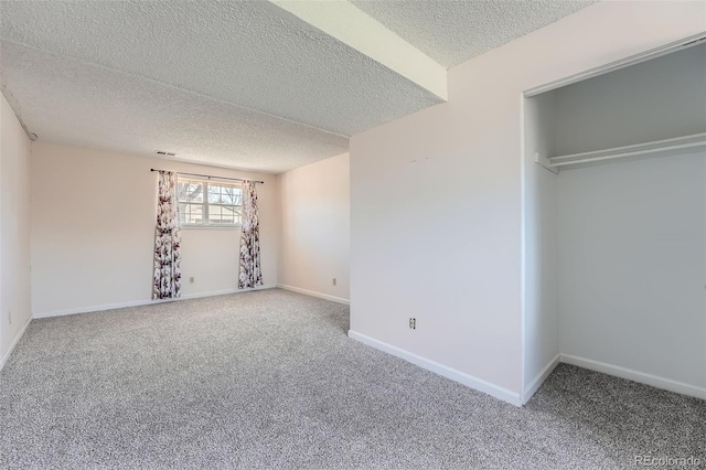 unfurnished bedroom with baseboards, a textured ceiling, carpet, and visible vents