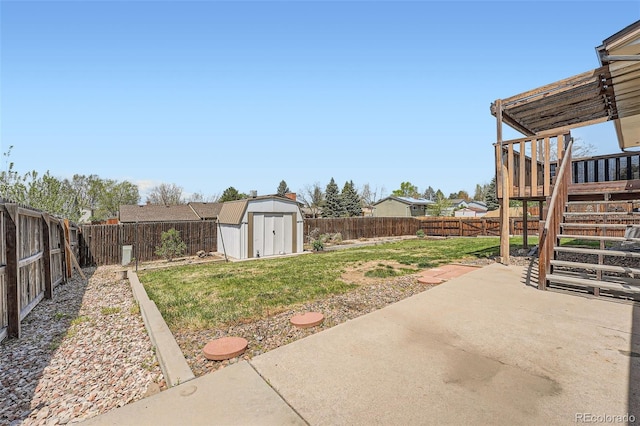 view of yard featuring a storage unit, a wooden deck, a fenced backyard, a patio area, and an outdoor structure