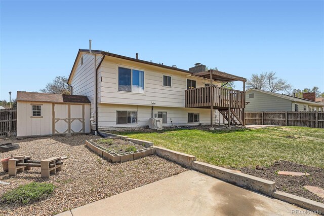 1207 S Memphis St, Aurora, CO 80017 - rear view of house with a fenced backyard, a storage unit, stairs, and a yard