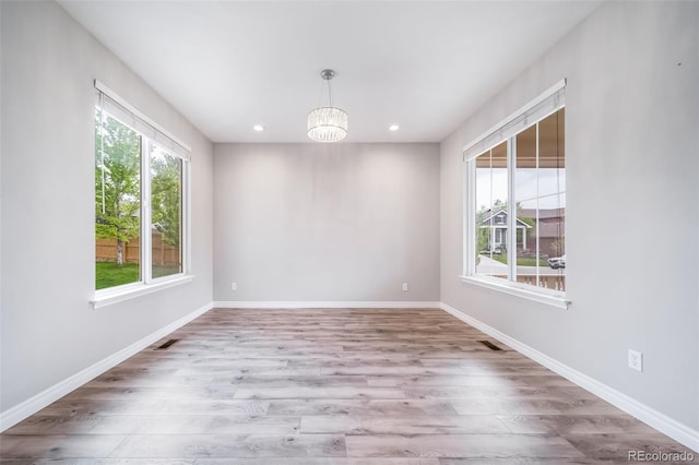 spare room featuring plenty of natural light, wood finished floors, a chandelier, recessed lighting, and baseboards