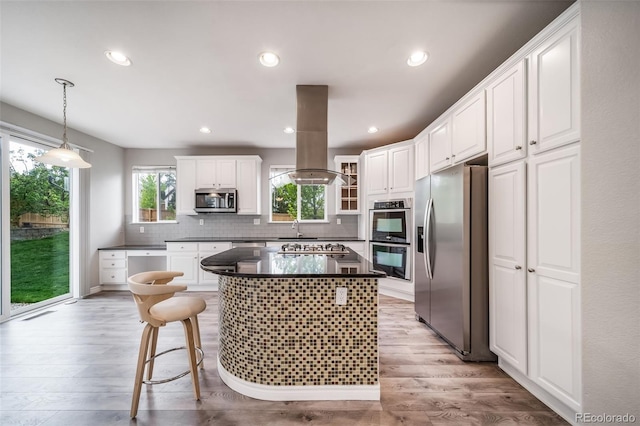 kitchen with stainless steel appliances, island exhaust hood, dark countertops, a sink, and white cabinets