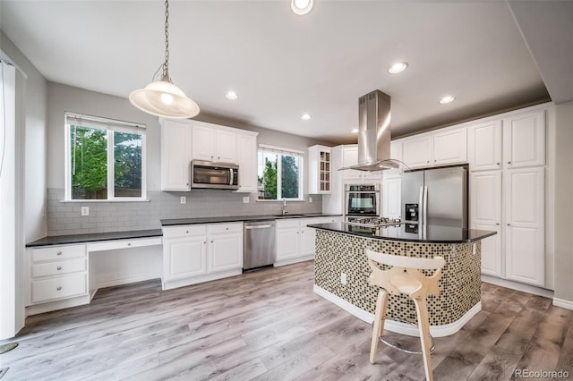 kitchen with stainless steel appliances, island range hood, dark countertops, a sink, and tasteful backsplash