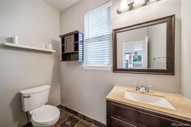 bathroom featuring toilet, vanity, and baseboards