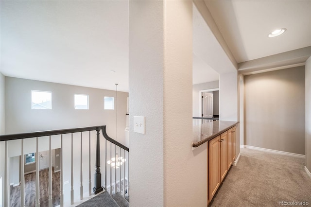 corridor featuring baseboards, light colored carpet, and an upstairs landing