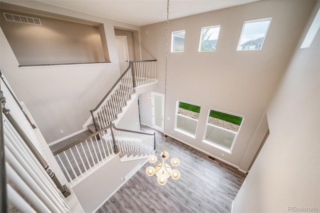 staircase featuring wood finished floors, a towering ceiling, and baseboards