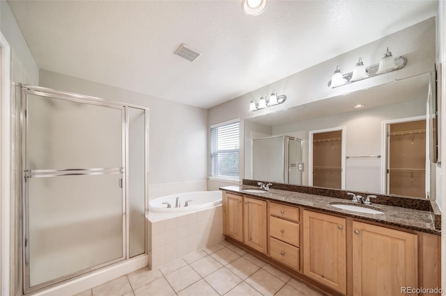 full bathroom with a shower stall, tile patterned flooring, a bath, a spacious closet, and double vanity