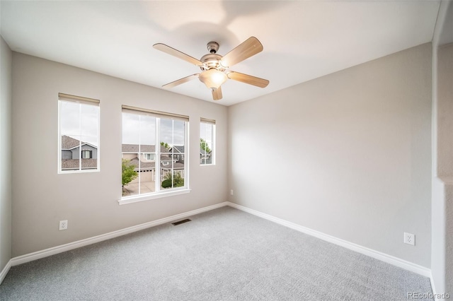carpeted spare room with baseboards and a ceiling fan