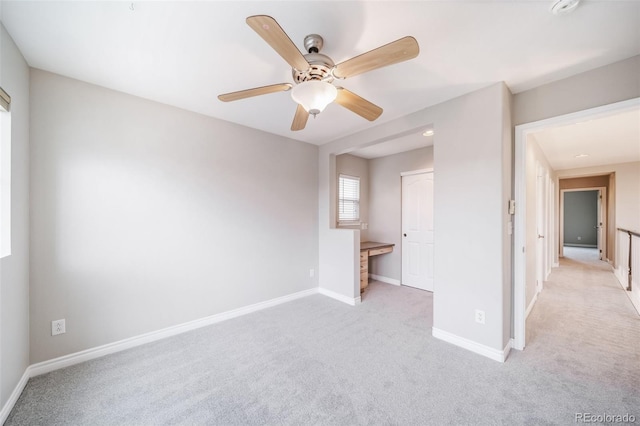 unfurnished bedroom with light colored carpet, baseboards, and a ceiling fan