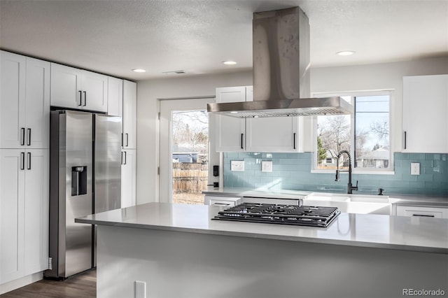 kitchen featuring white cabinets, appliances with stainless steel finishes, island exhaust hood, and sink