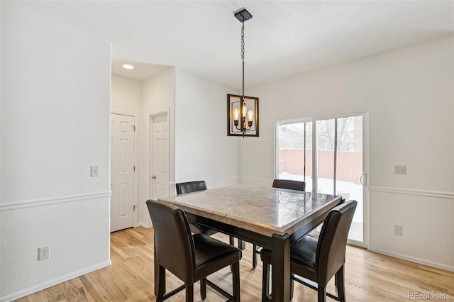 dining area with light hardwood / wood-style floors and an inviting chandelier