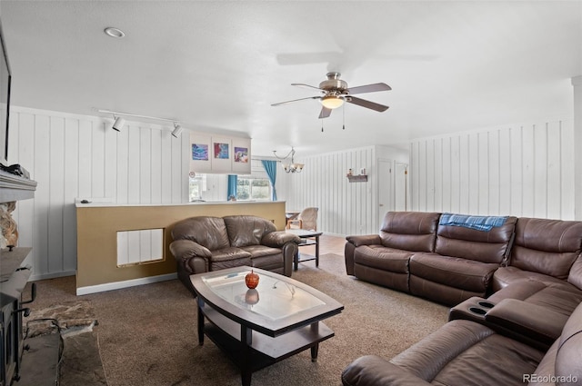 carpeted living area with a fireplace with raised hearth and ceiling fan with notable chandelier