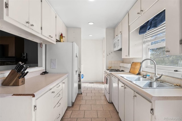 kitchen featuring white appliances, light countertops, white cabinetry, a sink, and light tile patterned flooring