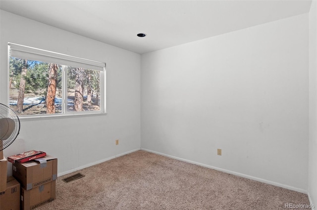 carpeted spare room featuring visible vents and baseboards