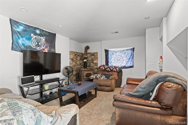 carpeted living room with a wood stove and visible vents