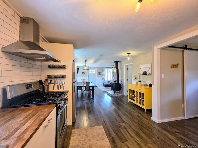 313 W Arkansas St, Buena Vista, CO 81211 - kitchen with wall chimney exhaust hood, a barn door, wooden counters, dark wood-type flooring, and appliances with stainless steel finishes