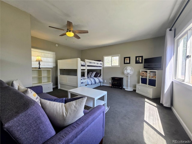 313 W Arkansas St, Buena Vista, CO 81211 - bedroom featuring dark carpet, ceiling fan, baseboards, and a wood stove