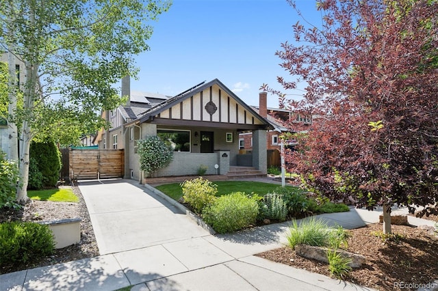 815 S Gaylord St, Denver, CO 80209 - tudor house featuring roof mounted solar panels, brick siding, a gate, and covered porch