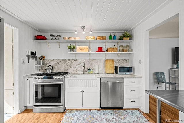 5465 Saulsbury Ct, Arvada, CO 80002 - kitchen with appliances with stainless steel finishes, open shelves, backsplash, white cabinets, and light wood-style floors