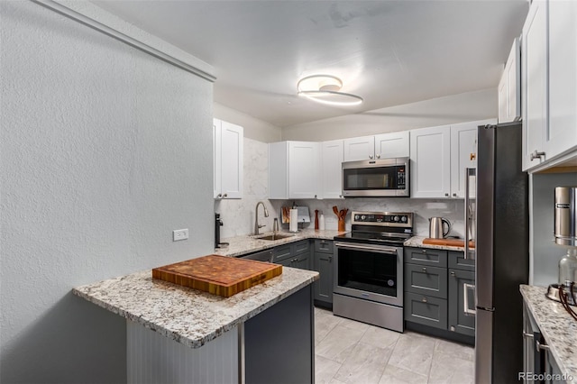 kitchen with tasteful backsplash, light tile flooring, gray cabinets, white cabinets, and appliances with stainless steel finishes