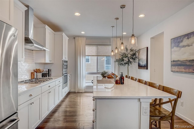 kitchen featuring sink, wall chimney exhaust hood, stainless steel appliances, a breakfast bar area, and a center island with sink