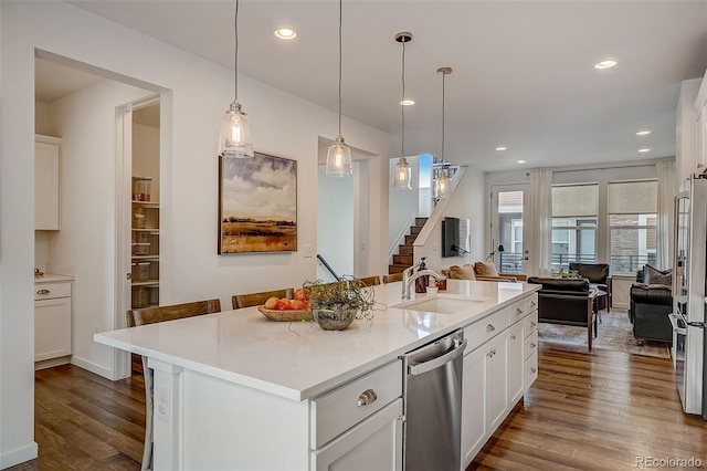 kitchen featuring pendant lighting, a kitchen island with sink, sink, appliances with stainless steel finishes, and white cabinetry