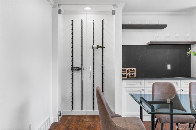 interior space with dark wood-type flooring, bar, and ornamental molding