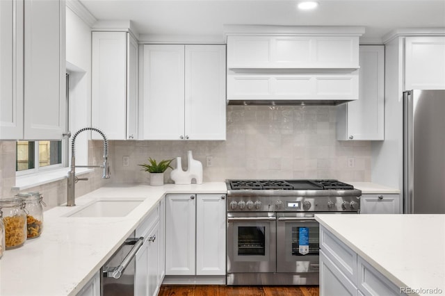 kitchen featuring stainless steel appliances, light stone countertops, sink, and white cabinets