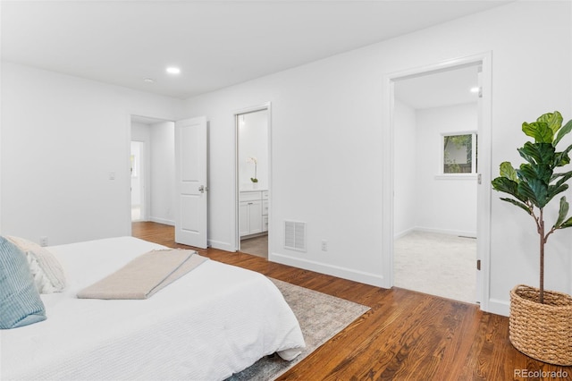 bedroom with ensuite bath and wood-type flooring