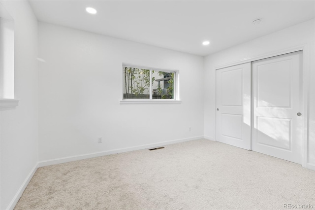 unfurnished bedroom with light colored carpet and a closet