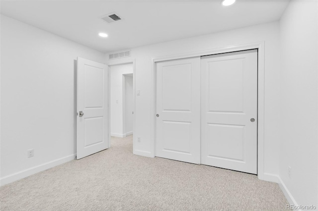 unfurnished bedroom featuring light colored carpet and a closet