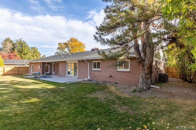 rear view of house with a patio, central AC unit, and a lawn