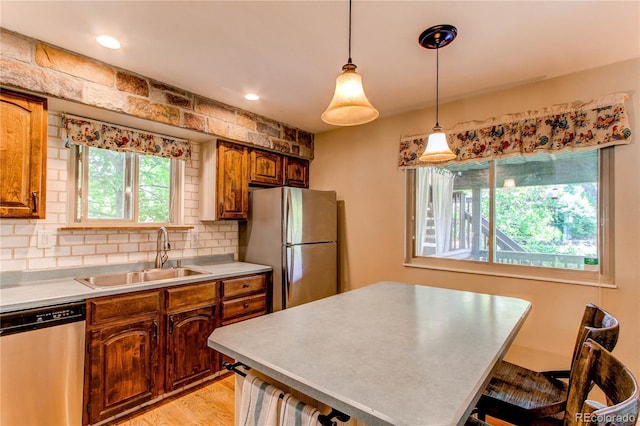 6687 Devinney Ct, Arvada, CO 80004 - kitchen featuring appliances with stainless steel finishes, a sink, light countertops, decorative backsplash, and a kitchen island