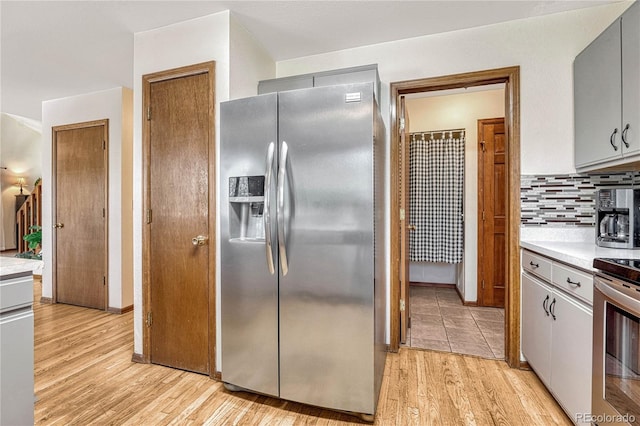 kitchen with stainless steel appliances, light wood-type flooring, tasteful backsplash, and gray cabinets