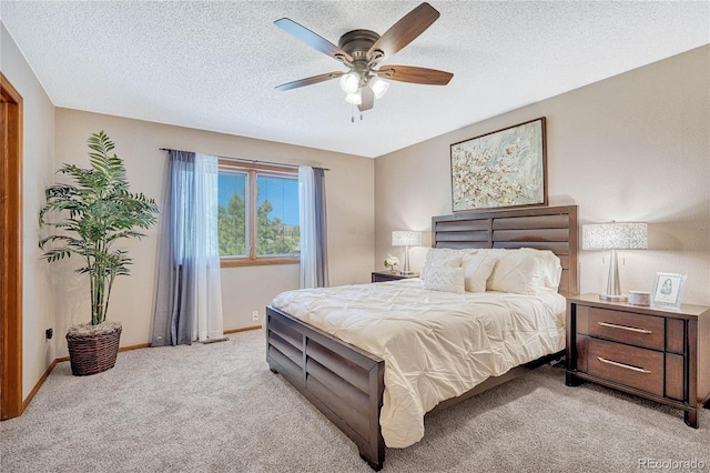 bedroom with light colored carpet, ceiling fan, and a textured ceiling