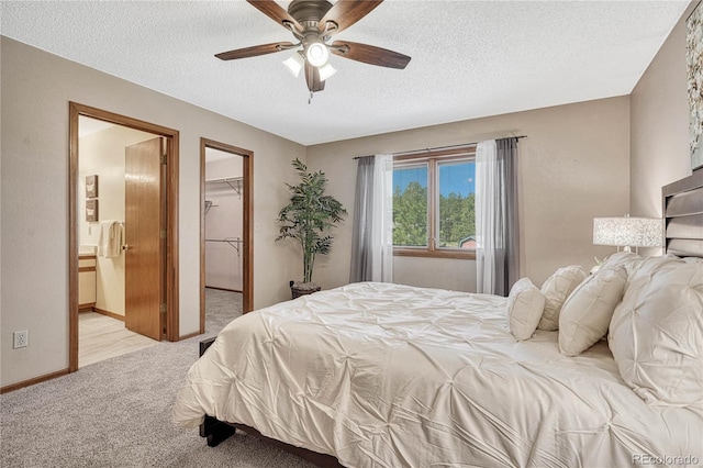 carpeted bedroom with a textured ceiling, a spacious closet, ensuite bathroom, a closet, and ceiling fan