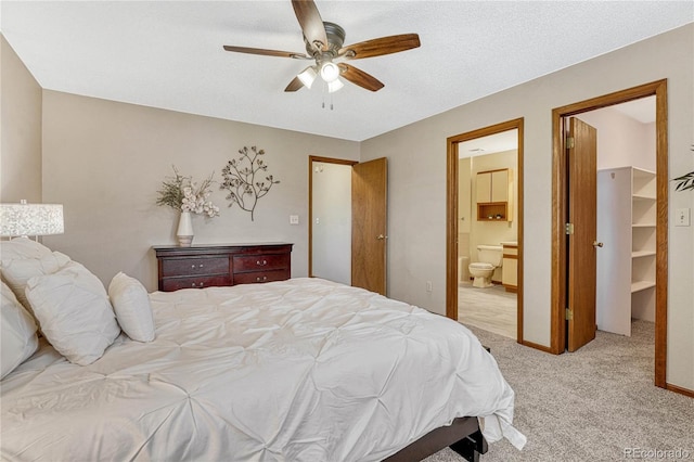 bedroom with light carpet, ceiling fan, a closet, a walk in closet, and ensuite bath