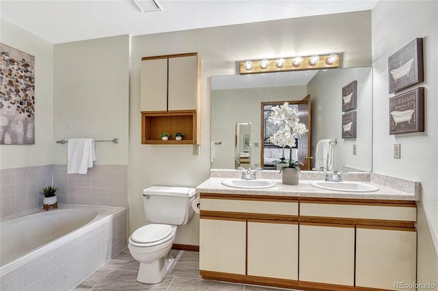 bathroom featuring toilet, tiled bath, tile patterned floors, and vanity