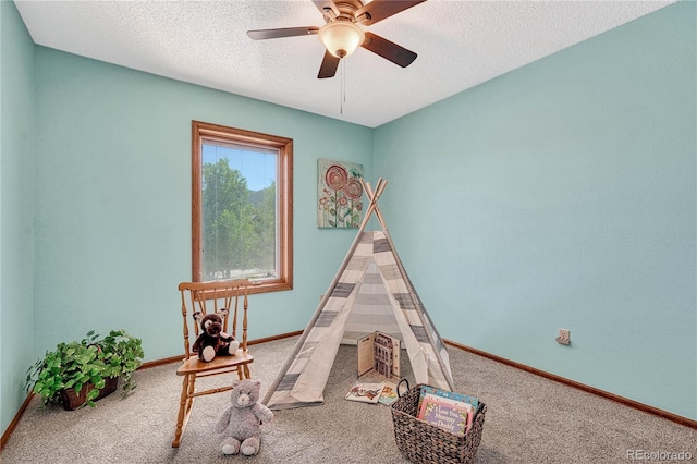 playroom with a textured ceiling, carpet floors, and ceiling fan