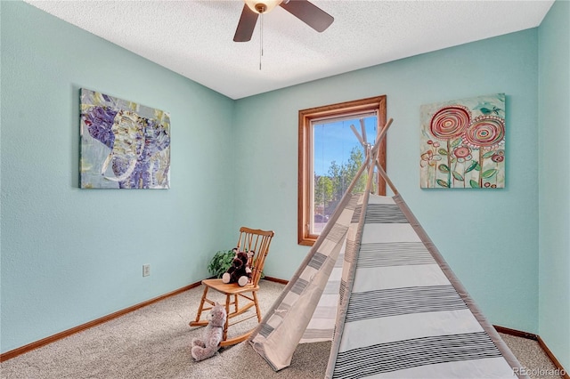 carpeted bedroom featuring ceiling fan and a textured ceiling