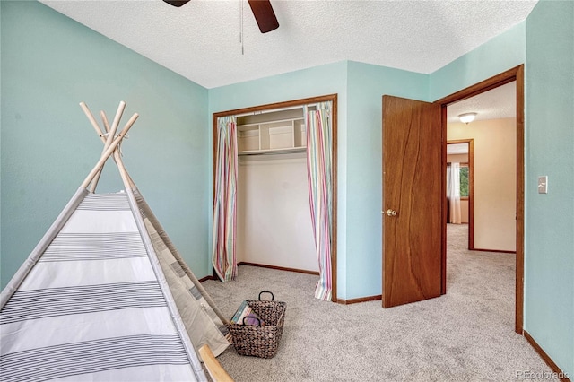 unfurnished bedroom with a closet, ceiling fan, a textured ceiling, and light colored carpet