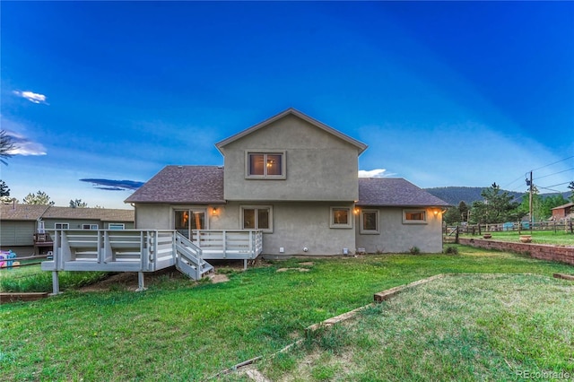 rear view of house featuring a deck and a lawn