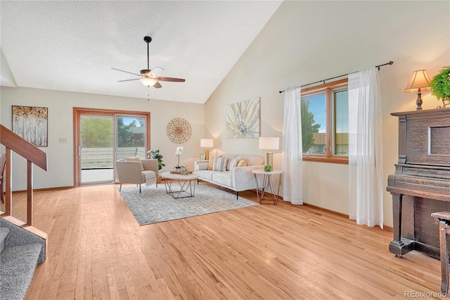 living room with lofted ceiling, a textured ceiling, light wood-type flooring, and ceiling fan