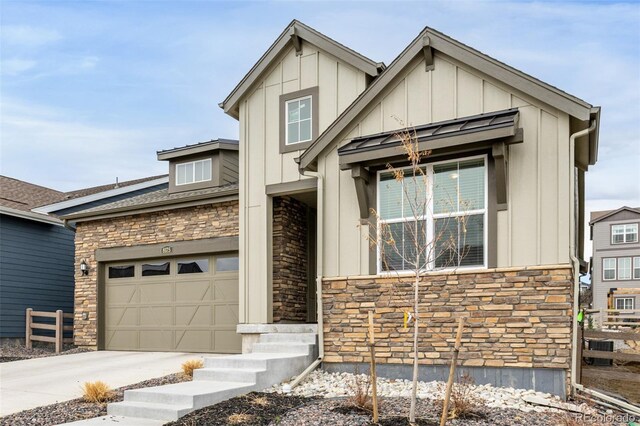 view of front of property with driveway, an attached garage, stone siding, and board and batten siding