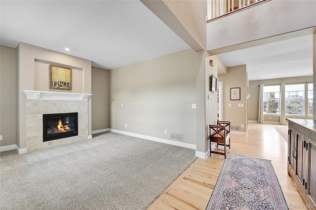 living room with a tiled fireplace and light wood-type flooring