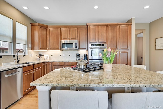 kitchen with light stone countertops, stainless steel appliances, sink, and a kitchen bar