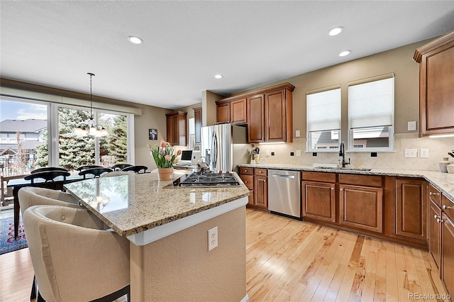 kitchen featuring sink, a breakfast bar, hanging light fixtures, stainless steel appliances, and a center island