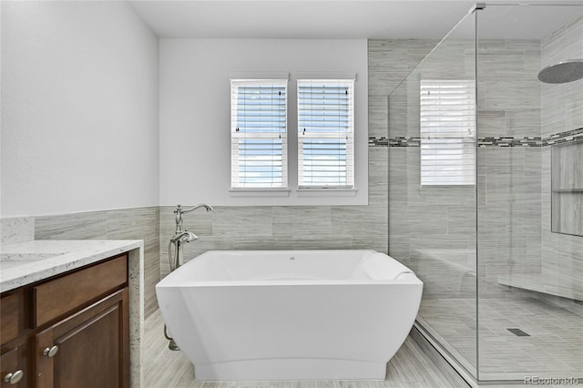 bathroom with vanity, plus walk in shower, and tile walls