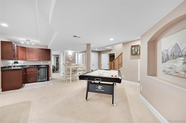 recreation room featuring track lighting, beverage cooler, sink, and light carpet